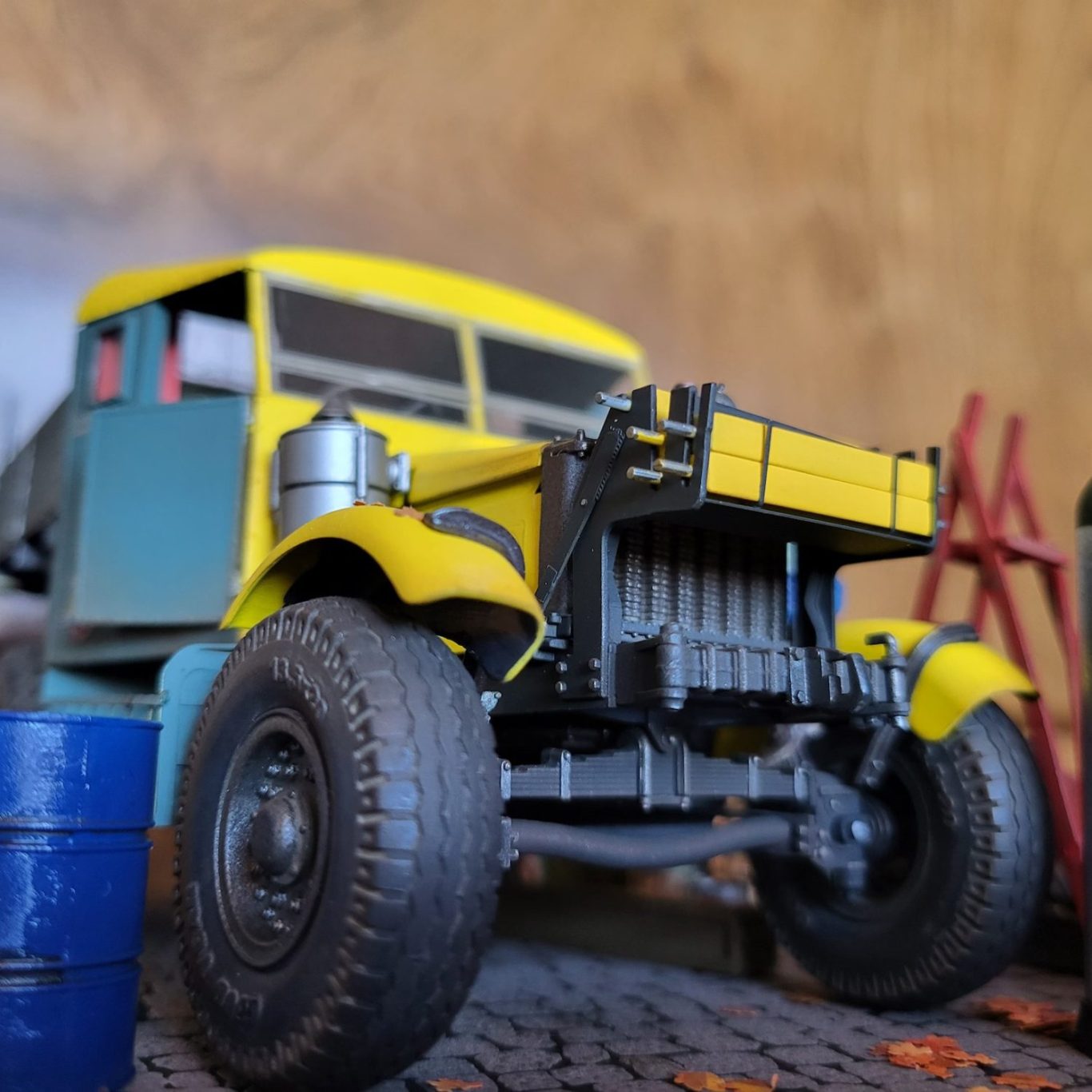 Yellow vintage truck with a flatbed, set against a rustic background with barrels.