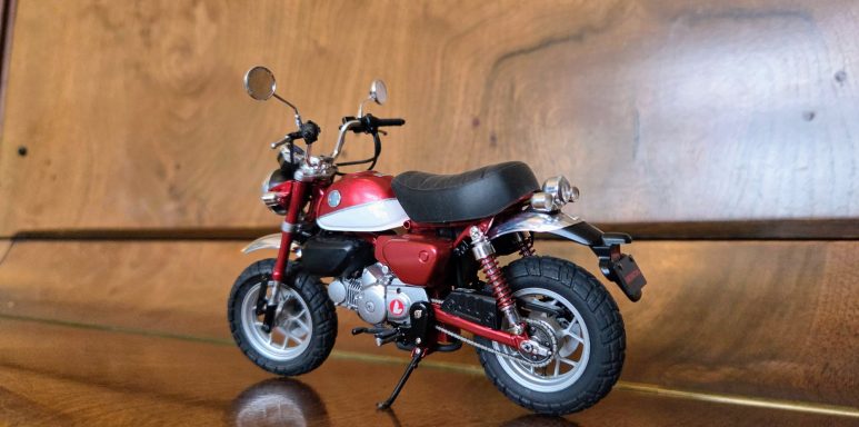 A small red and white toy motorcycle displayed on a wooden surface.
