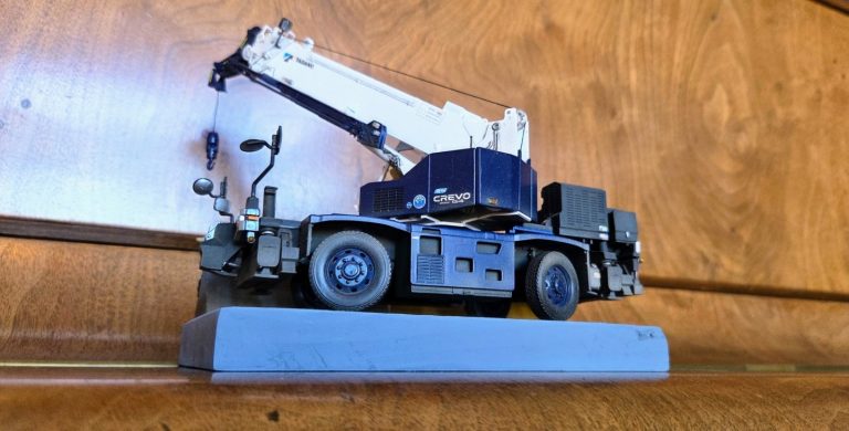 Model of a crane truck displayed on a wooden shelf.