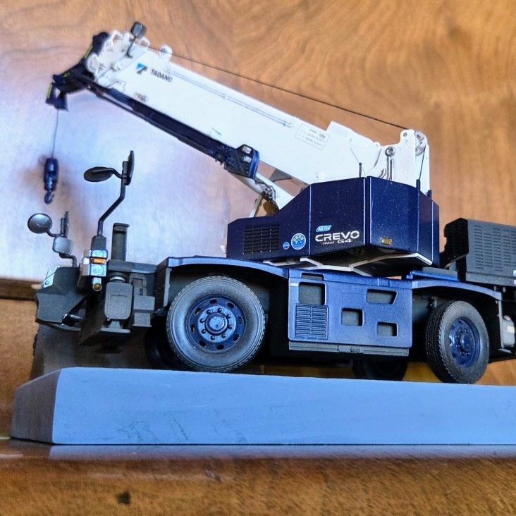 A model crane truck with a blue and white design on a grey base.
