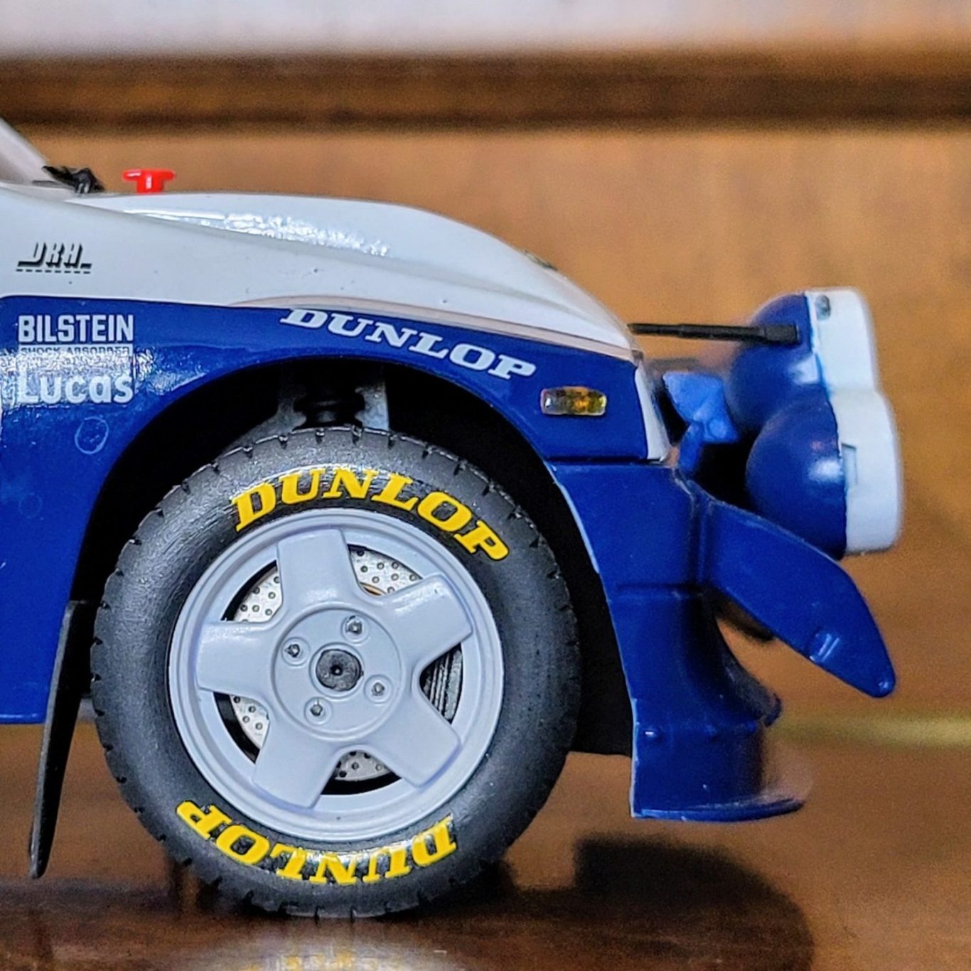 Close-up of a blue race car model with a Dunlop tyre and detailed bodywork.