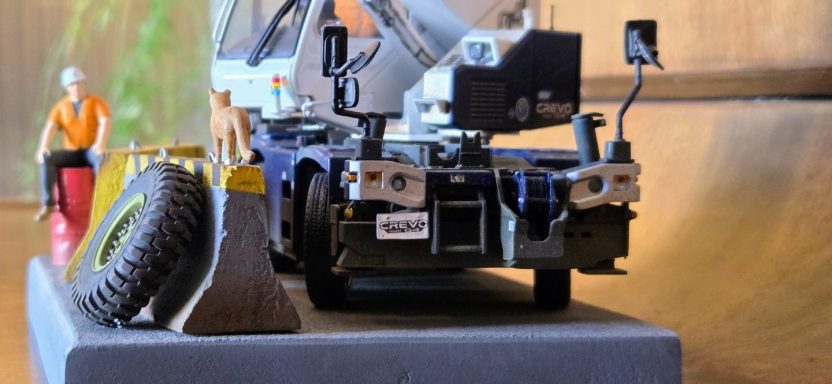 Model construction scene with a crane, figures, and a large tyre on display.
