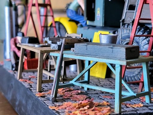 A model scene featuring various workbenches, tools, and a cluttered workshop environment.