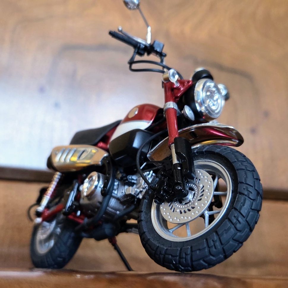 A detailed model of a motorcycle with a red and black design and rugged tyres.