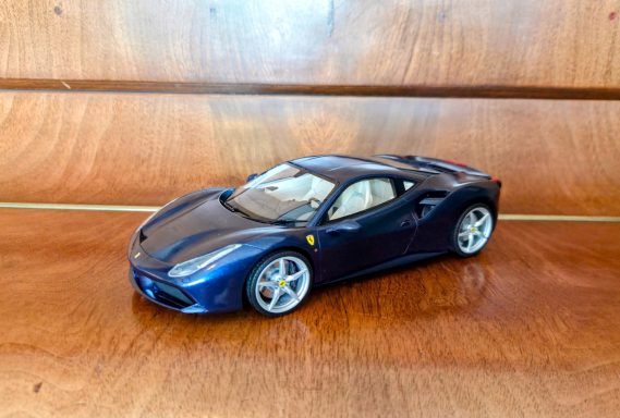 Model of a blue Ferrari 488, displayed on a wooden surface.