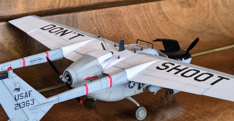 Model aircraft with "DON'T SHOOT" markings and a detailed body, positioned on a wooden surface.