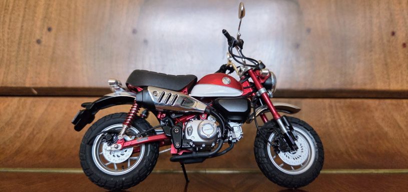 scale model Red and black motorcycle with a retro design against a wooden background.