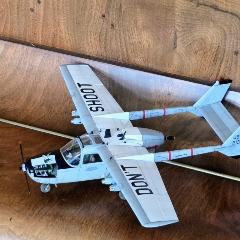 Model airplane with "DON'T SHOOT" written on the wings, resting on a wooden surface.