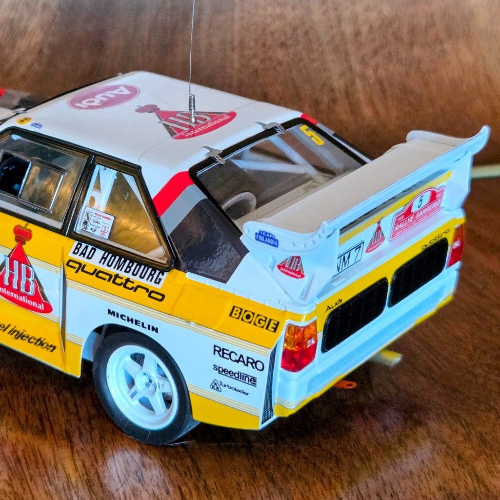 Model car of a rally vehicle, featuring a distinctive white and yellow livery with sponsor logos.