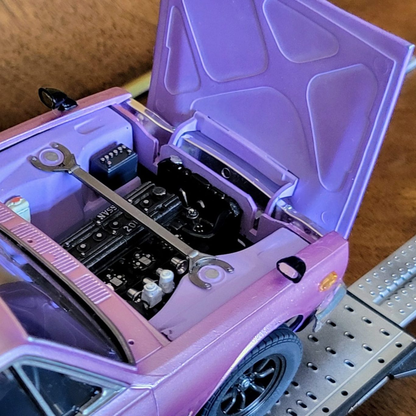Purple model car with the hood open, showing detailed engine and tools.